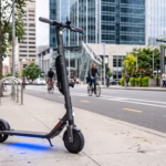 Segway-Ninebot ES2 electric scooter parked on a city sidewalk at dusk with blue ambient under-deck lighting glowing.