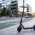 Xiaomi Mi M365 Pro electric commuter scooter parked next to a green cycle lane on a modern city street at sunrise.